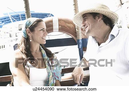 Stock Image - Mid adult couple looking at each other and smiling. Fotosearch