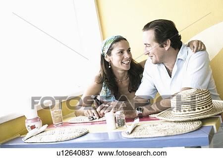Mid adult couple sitting in a restaurant View Large Photo Image Stock Photo - Mid adult couple sitting in a restaurant. Fotosearch