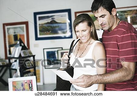 Stock Image - Mid adult couple standing in a paintings store. Fotosearch