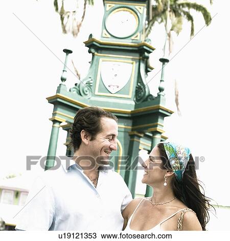 Stock Image - Mid adult couple standing with their arms around each other and smiling. Fotosearch