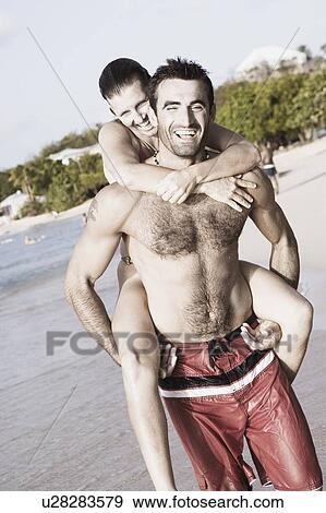 Mid adult man riding piggyback on a mid adult woman on the beach View Large Photo Image Stock Photo - Mid adult man riding piggyback on a mid adult woman on the beach. Fotosearch