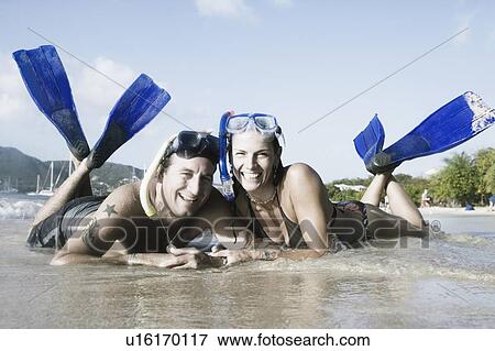 Stock Photo - Portrait of a mid adult couple lying on the beach. Fotosearch