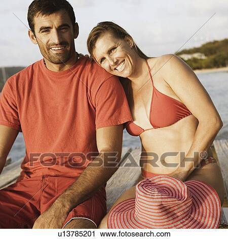 Portrait of a mid adult couple sitting on a pier and smiling View Large Photo Image Stock Image - Portrait of a mid adult couple sitting on a pier and smiling. Fotosearch
