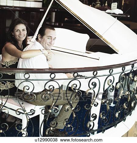 Portrait of a mid adult man playing a piano with a mid adult woman smiling beside him View Large Photo Image Stock Photo - Portrait of a mid adult man playing a piano with a mid adult woman smiling beside him. Fotosearch