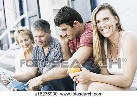 Portrait of a mid adult woman sitting with her friends on steps View Large Photo Image Stock Image - Portrait of a mid adult woman sitting with her friends on steps. Fotosearch