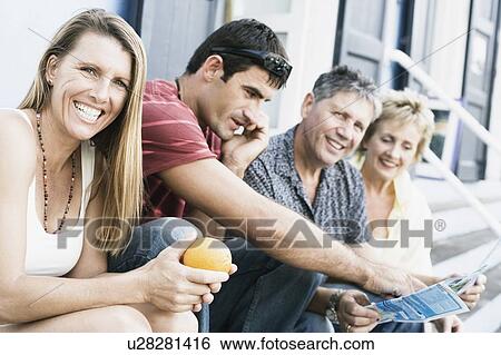 Stock Photograph - Portrait of a mid adult woman sitting with her friends on steps. Fotosearch