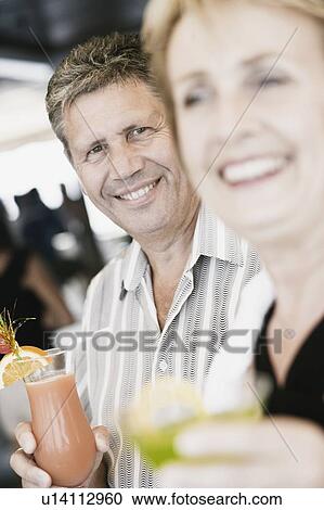 Stock Image - Senior man and a mature woman holding glasses of cocktail. Fotosearch