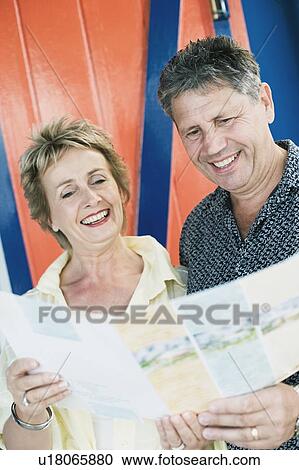 Stock Image - Senior man and a mature woman reading a brochure. Fotosearch