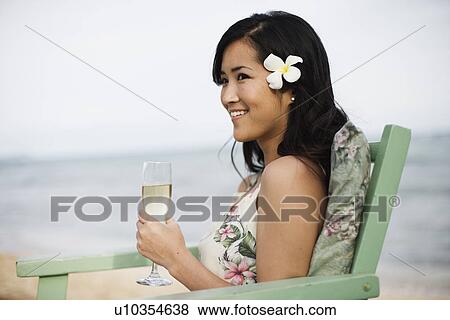 Stock Photo - A woman holding wineglass at beach. Fotosearch