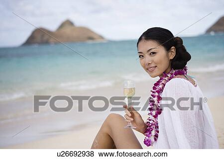 A young woman holding wineglass sitting at beach View Large Photo Image Stock Photo - A young woman holding wineglass sitting at beach. Fotosearch