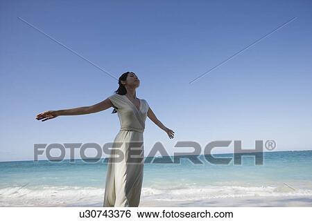 A young woman standing on beach View Large Photo Image Stock Photograph - A young woman standing on beach. Fotosearch