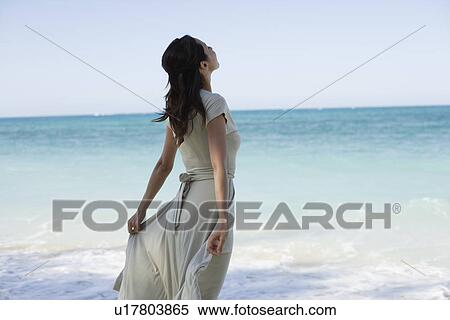 Stock Photography - A young woman standing on beach. Fotosearch
