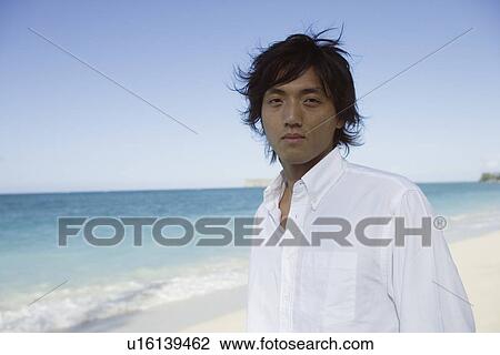 Portrait of a young man standing at beach View Large Photo Image Stock Image - Portrait of a young man standing at beach. Fotosearch