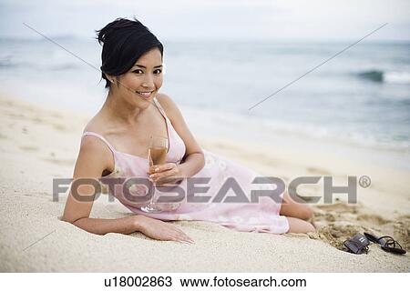 Portrait of a young woman lying on sand with wineglass View Large Photo Image Stock Image - Portrait of a young woman lying on sand with wineglass. Fotosearch