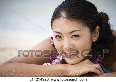 Portrait of a young woman lying on sand at beach View Large Photo Image Stock Photograph - Portrait of a young woman lying on sand at beach. Fotosearch