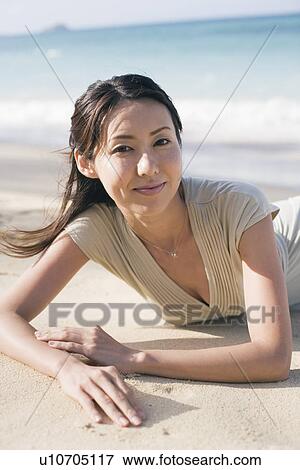 Portrait of young woman lying on beach View Large Photo Image Stock Photo - Portrait of young woman lying on beach. Fotosearch