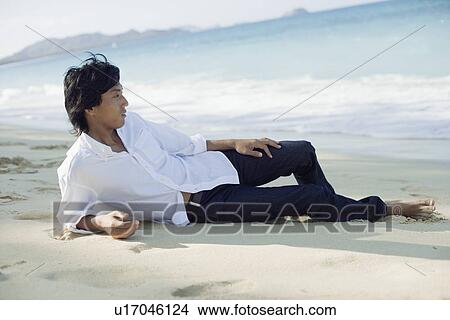 Profile of a young man lying on sand at beach View Large Photo Image Picture - Profile of a young man lying on sand at beach. Fotosearch