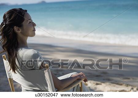 Profile of a young woman sitting on chair View Large Photo Image Stock Photo - Profile of a young woman sitting on chair. Fotosearch