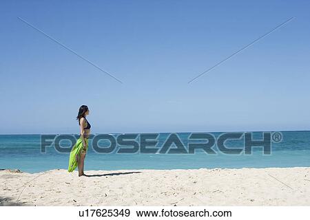 Stock Photo - Profile of a young woman standing on beach. Fotosearch