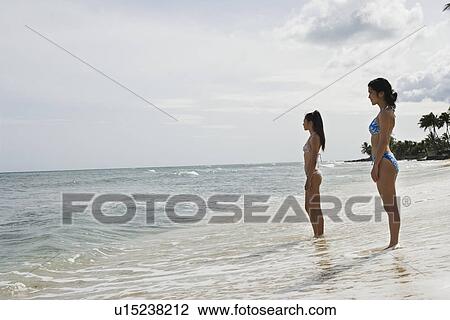 Stock Image - Profile of young women standing on sea. Fotosearch