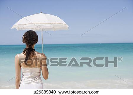 Stock Image - Rear view of a woman standing on beach. Fotosearch