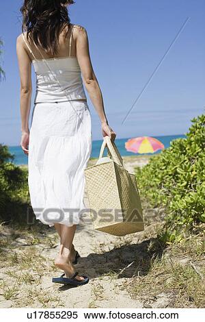 Stock Photography -  rear view of a woman walking towards beach. Fotosearch