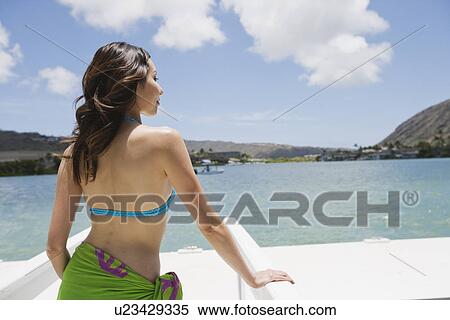 Rear view of a young woman standing on a pier View Large Photo Image Stock Photography - Rear view of a young woman standing on a pier. Fotosearch