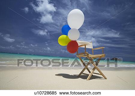 Stock Photography - View of air balloons on wooden chair at beach. Fotosearch