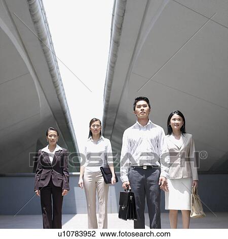 Stock Image - Businessman standing with three businesswomen. Fotosearch