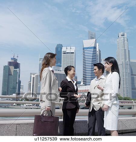 Stock Photo - Businessman talking to three businesswomen. Fotosearch