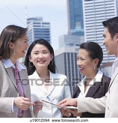Picture - Close-up of a businessman showing a document to three businesswomen. Fotosearch