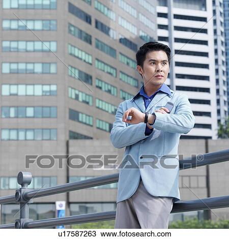 Stock Image - Low angle view of a businessman leaning against a railing. Fotosearch
