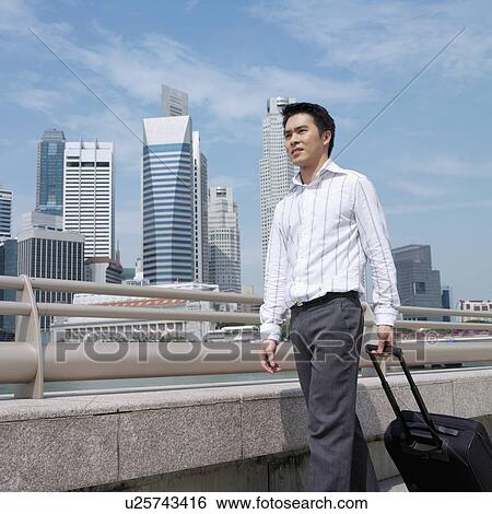 Low angle view of a businessman pulling a suitcase View Large Photo Image Stock Photograph - Low angle view of a businessman pulling a suitcase. Fotosearch