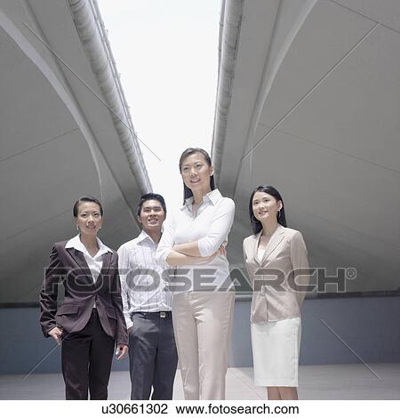 Stock Image - Low angle view of a businessman standing with three businesswomen. Fotosearch