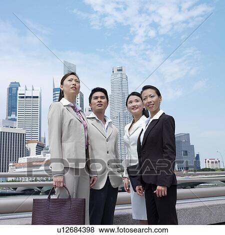 Stock Photo - Low angle view of a businessman pointing to three businesswomen. Fotosearch