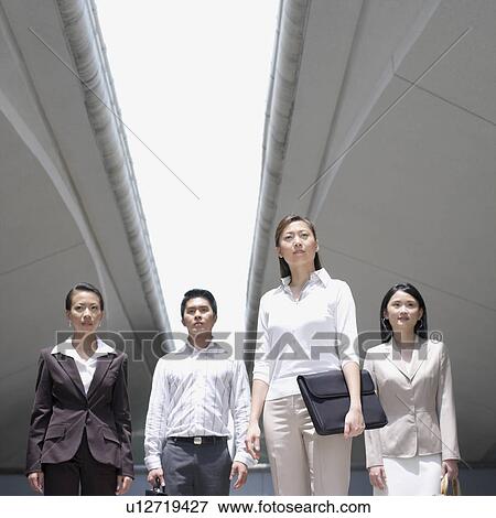 Stock Photo - Low angle view of a businessman standing with three businesswomen. Fotosearch