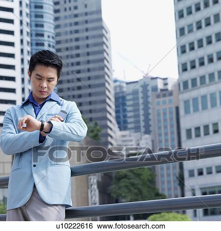 Low angle view of a businessman checking the time View Large Photo Image Stock Photograph - Low angle view of a businessman checking the time. Fotosearch