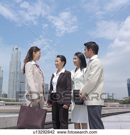 Stock Image - Low angle view of a businessman talking to three businesswomen. Fotosearch