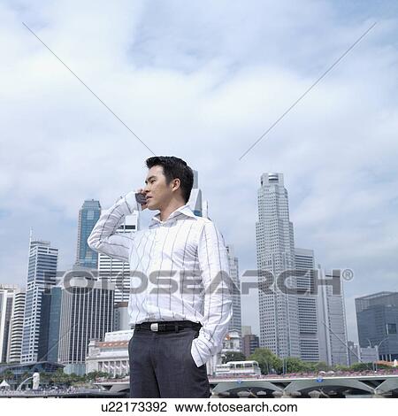 Stock Image - Low angle view of a businessman talking on a mobile phone. Fotosearch