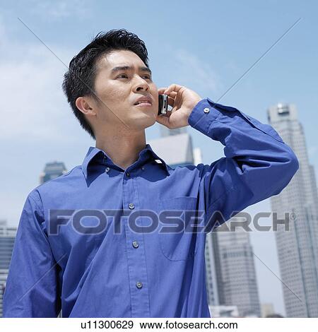 Low angle view of a businessman talking on a mobile phone View Large Photo Image Stock Photo - Low angle view of a businessman talking on a mobile phone. Fotosearch