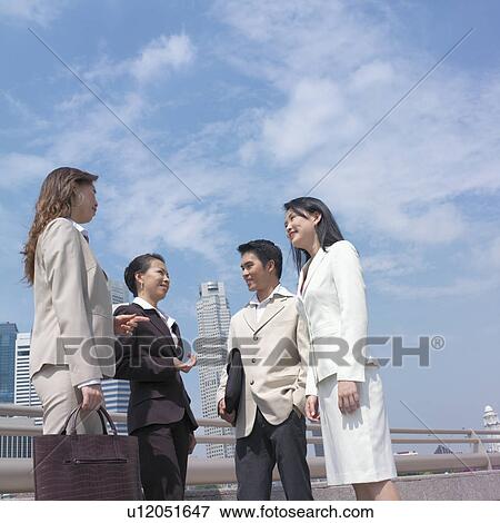 Low angle view of a businessman talking to three businesswomen View Large Photo Image Stock Photo - Low angle view of a businessman talking to three businesswomen. Fotosearch