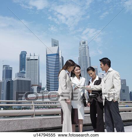 Stock Photography - Low angle view of a businessman talking to three businesswomen. Fotosearch