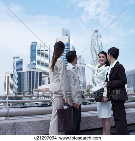 Picture - Low angle view of a businesswoman pointing towards buildings. Fotosearch