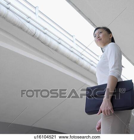 Low angle view of a businesswoman holding a briefcase View Large Photo Image Stock Image - Low angle view of a businesswoman holding a briefcase. Fotosearch