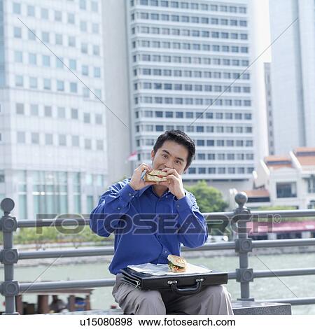 Portrait of a businessman eating a burger View Large Photo Image Stock Photo - Portrait of a businessman eating a burger. Fotosearch