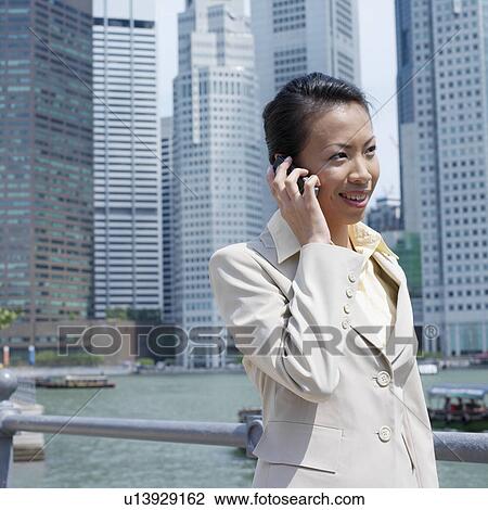 Stock Image - Side profile of a businesswoman talking on a mobile phone. Fotosearch