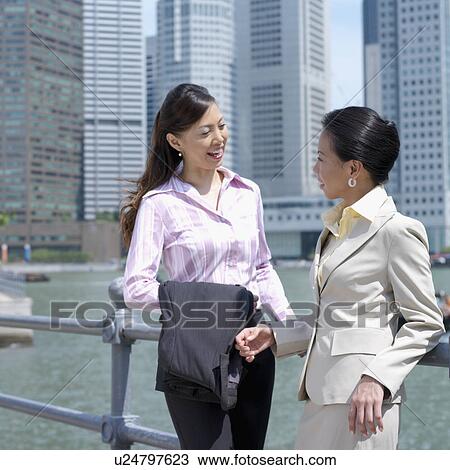 Two businesswomen leaning against a railing View Large Photo Image Stock Image - Two businesswomen leaning against a railing. Fotosearch