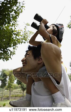 A boy on father's shoulder, looking into binoculars View Large Photo Image Stock Image - A boy on father's shoulder, looking into binoculars. Fotosearch