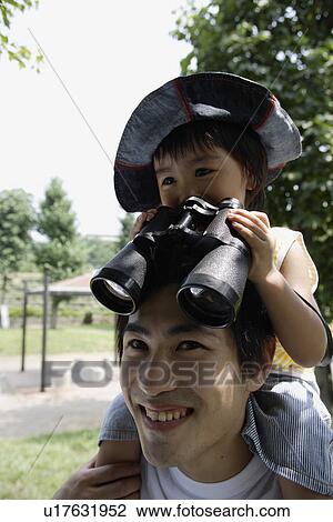 Stock Image - A boy on father's shoulder, looking into binoculars. Fotosearch