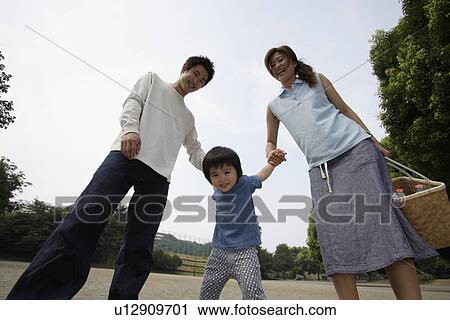 Stock Image - A boy standing between mother and father. Fotosearch
